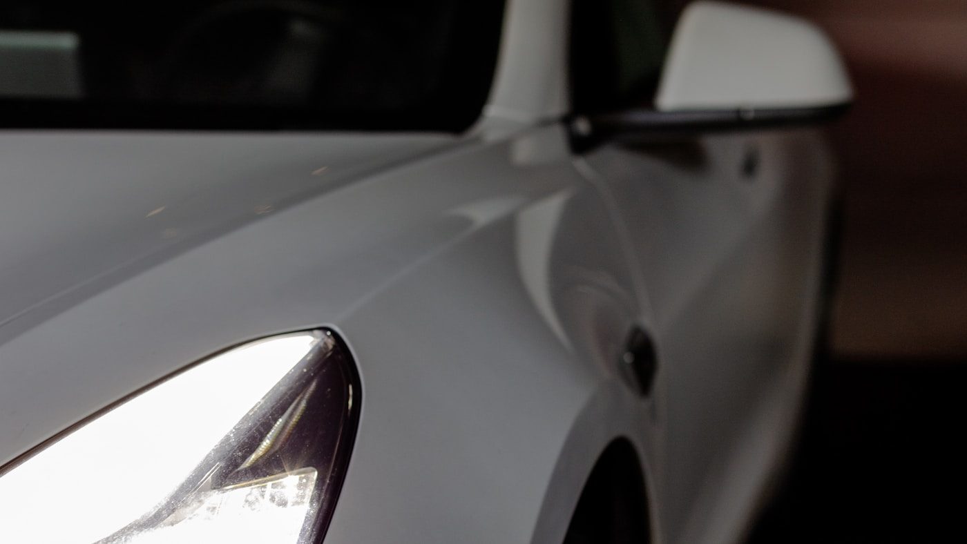 Close-up of the glossy front end of a white sports car protected with clear paint protection film