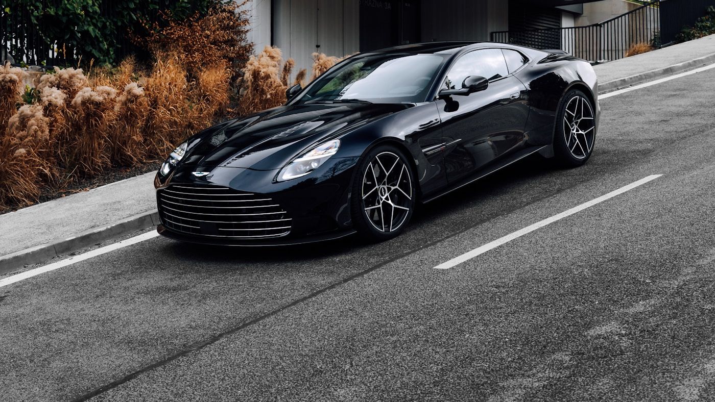 A glossy black sports car photographed in profile, every painted panel wrapped in protection film